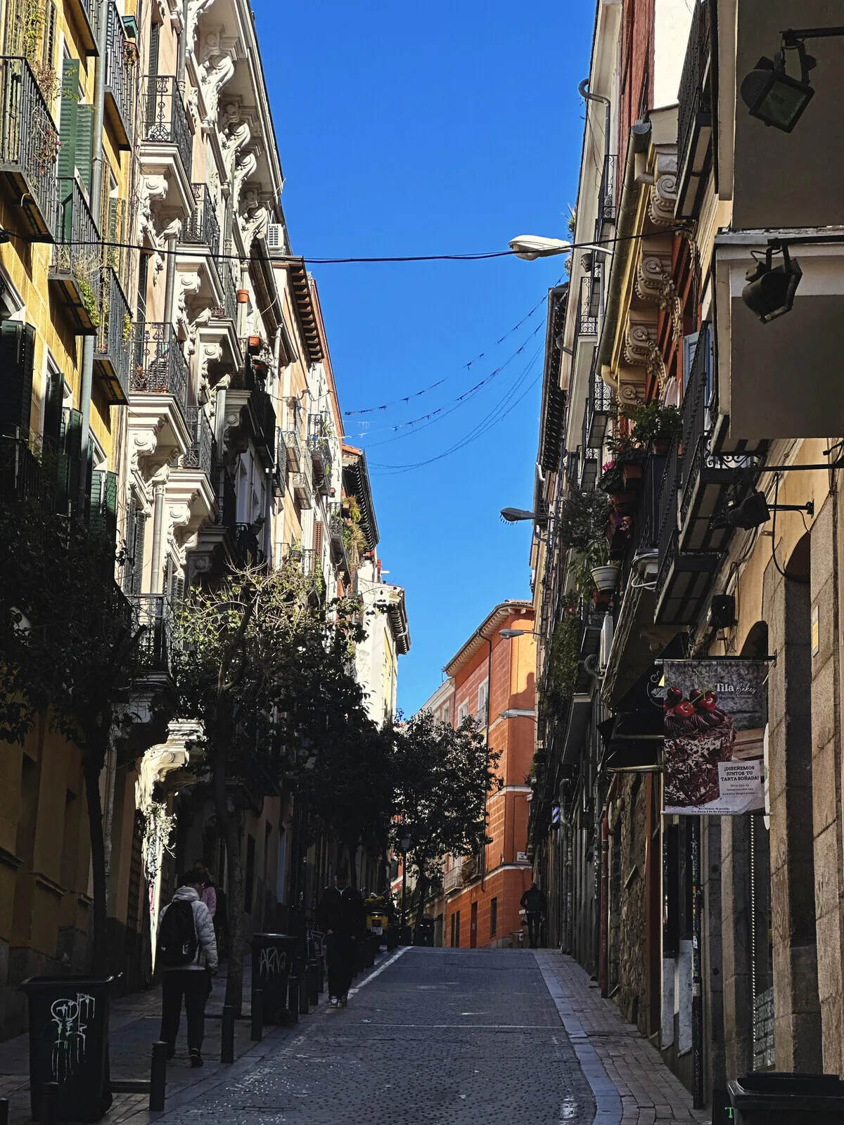 A narrow street in Madrid with balconies on both sides.