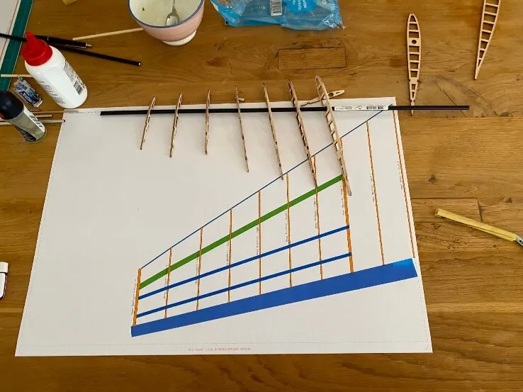 The printed plan on the table with the laser-cut balsa ribs and spars lying on it.